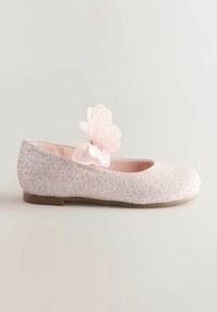 Ballerine rose étincelante avec une décoration papillon en tissu doux sur le dessus et une semelle plate marron, présentée sur un fond uni.