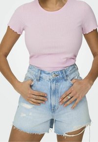 Světle růžový krátký rukáv žebrovaný top zkombinovaný s vysokým pasem roztrhanými denimi šortkami ve světle modré barvě. Obsahuje roztrhaný lem a jemn�é vyblednutí.