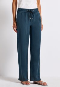 Pantaloni turchesi, leggeri e svasati con vita elasticizzata e cordini con puntali in argento; texture liscia e gambe ampie per il massimo comfort.