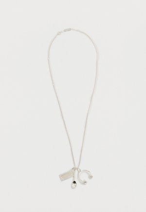 Collier en argent avec trois pendentifs : un clavier, une cuillère et un casque audio sur une chaîne fine, sur fond blanc.