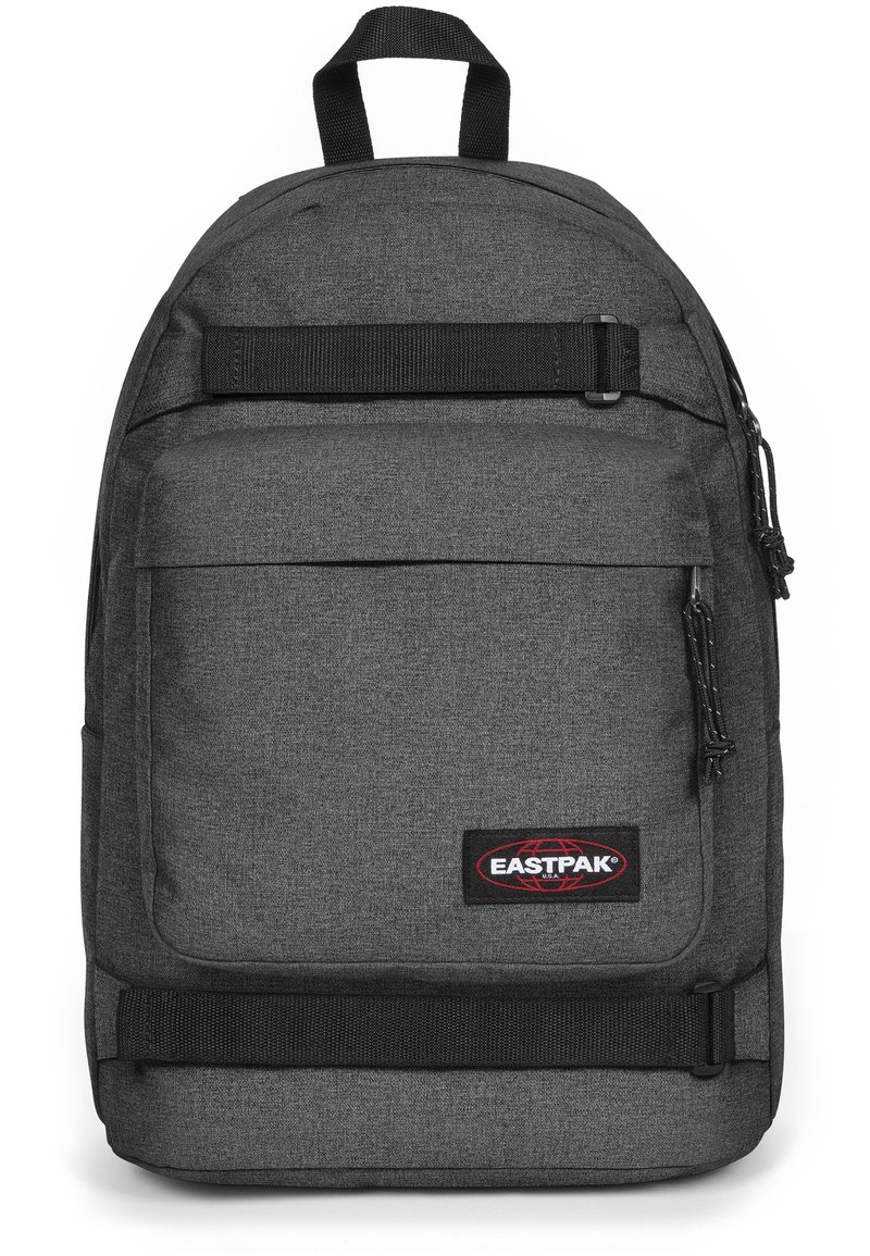 Sac à dos en tissu gris avec des bretelles réglables, une poche avant et un patch logo. Il dispose d'une poignée supérieure et de zips avec cordons.