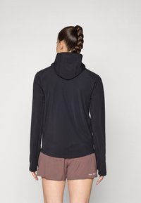 Black hoodie with a high collar and long sleeves, displayed from the back. Paired with brown shorts, exposing part of the torso.