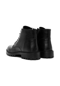 Botas de tobillo de cuero negro con un acabado texturizado, punta redonda y suela de goma gruesa; cuentan con cordones y una cremallera en la parte trasera.