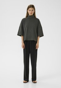 Lyhythihainen, hiilenharmaa poolopaita yhdistettynä mustiin, leveälahkeisiin housuihin. Silkkinen kangas ja rento istuvuus. Minimalistinen estetiikka.
