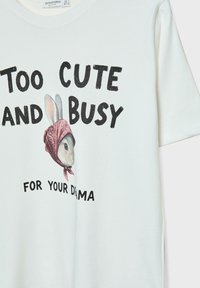 T-shirt in cotone di un leggero crema con una grafica di un coniglio che indossa un bandana rosa, con il testo "TROPPO CARINO E OCCUPATO PER LA TUA DRAMMATURGIA."