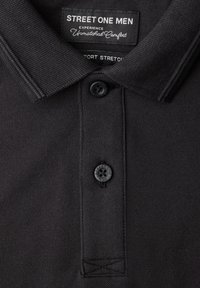 Col polo pour homme noir avec deux boutons, étiquette "Street One Men" et tissu en maille texturée.
