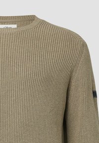 Beiger Strickpullover mit rundem Halsausschnitt und geripptem Textur. Verfügt über ein Logopatch am linken Ärmel. Entworfen für eine enganliegende Passform.