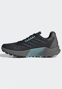 Scarpa sportiva nera con tomaia in rete, accenti blu chiaro, suola grigia robusta e pannelli testurizzati; progettata per terreni esterni.