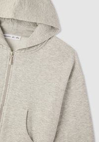 Felpa grigia con zip realizzata in un morbido tessuto testurizzato. Presenta un cappuccio, tasca anteriore e una vestibilità leggermente oversize.