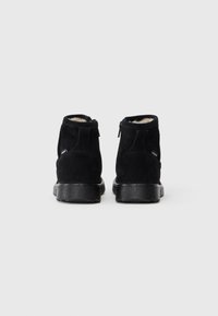 Botines de ante negros con una suela de goma texturizada, que cuentan con un cierre lateral para un fácil acceso y un suave forro interior.