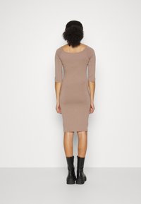 Vestido ajustado em mauve com mangas até ao cotovelo e saia até ao joelho. Feito de material suave; usado com botas pretas robustas.