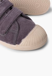 Chaussure à bride Velcro en velours côtelé gris foncé texturé, avec un embout en caoutchouc beige clair et une semelle flexible à motif.