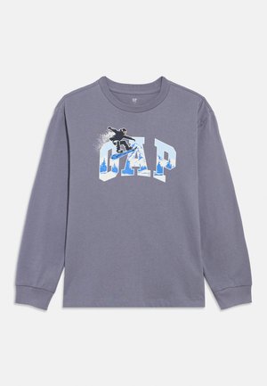 Pilko ilgomis rankovėmis medvilninis marškinėlis su grafika, vaizduojančia snieglentę ir žodžiu „GAP“ mėlyna ir balta spalvomis, su ribotais rankogių galais.