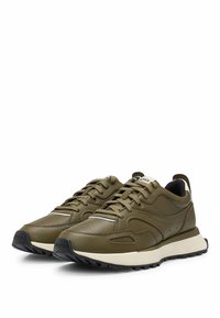 Olive green sneakers with a perforated leather upper, textile lining, black rubber outsole, and contrasting white midsole. Features lace-up design.