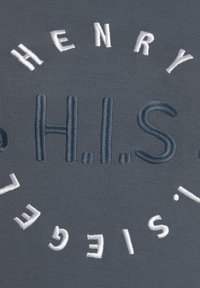 Textil gris con letras bordadas. Presenta "H.E.N.R.Y." y "H.I.S." en hilo azul y blanco, diseño circular, textura suave.