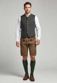Šedý vesta s knoflíkovým zapínáním, bílá košile, hnědé šortky s vyšívanými detaily, zelené podkolenky a hnědé boty.
