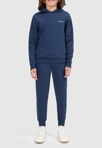 Navyblauwe sweatshirt en joggingsbroek van zachte stof; mouwen van gemiddelde lengte, ribgebreide boorden en een klein logo op de borst en het been.