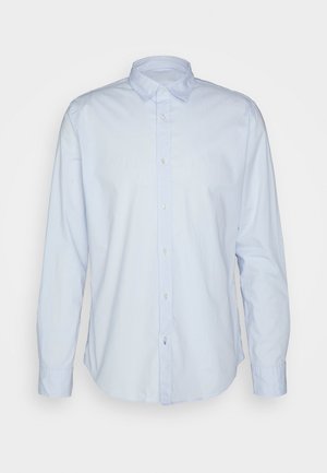Chemise à manches longues bleu clair en coton, avec un col boutonné, des boutons sur le devant et un ourlet droit avec des bords légèrement arrondis.
