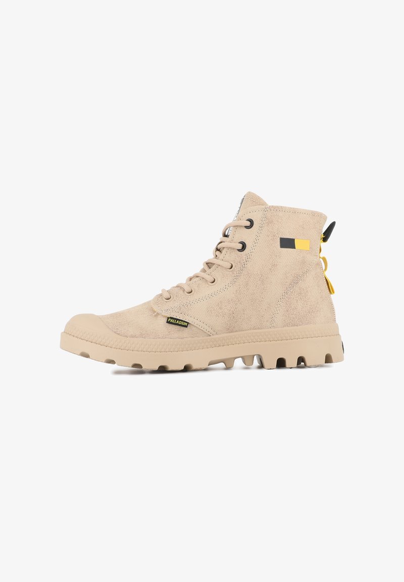 Botas altas beige hechas de tejido texturizado, con suela de goma, parte delantera con cordones y pequeña etiqueta de logo con acentos en amarillo y negro.