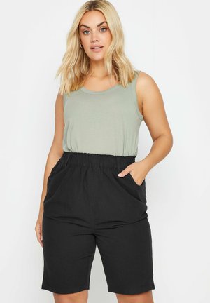 Lys grøn tanktop med rund halsudskæring, parret med sorte knælange shorts med elastisk liv og sidelommer.
