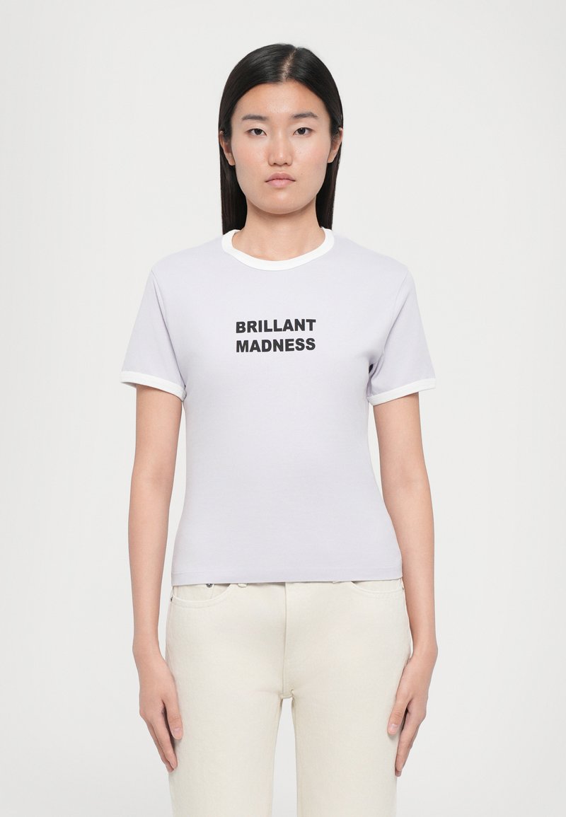Tricou din bumbac lavandă deschisă, cu guler și manșete albe, având textul negru "BRILLANT MADNESS" centrat pe față. Croială clasică.