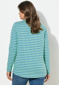 Pitkähihainen paita vaaleansinisissä ja neonkirkkaissa vihreissä raidoissa. Pehmeää puuvillamateriaalia, rento istuvuus ja kaareva helma. Hihansuissa nappikoristukset.