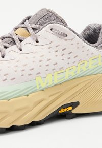 Chaussure de randonnée légère avec une tige gris clair texturée, des accents vert menthe et une semelle beige robuste avec la marque Vibram.