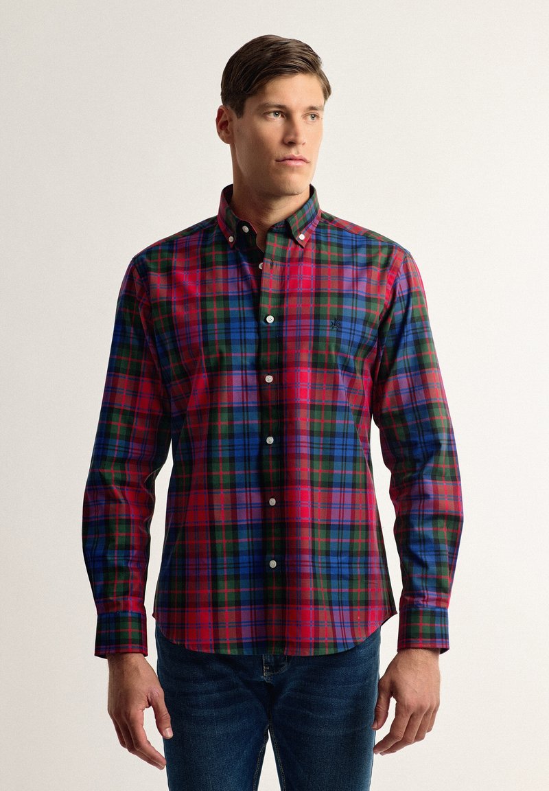 Camisa de cuadros en tonos rojos, azules y verdes. Presenta un cuello clásico, mangas largas y un logo en la parte izquierda del pecho.