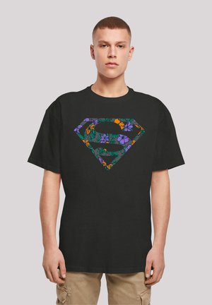 Black cotton t-shirt featuring a colorful floral print of a superhero emblem on the front, with short sleeves and a relaxed fit.