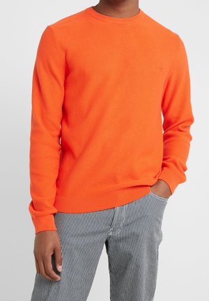 Helle orange Crewneck-Pullover mit einem strukturierten Strickmuster. Verfügt über lange Ärmel und gerippte Bündchen, kombiniert mit gestreiften Hosen.
