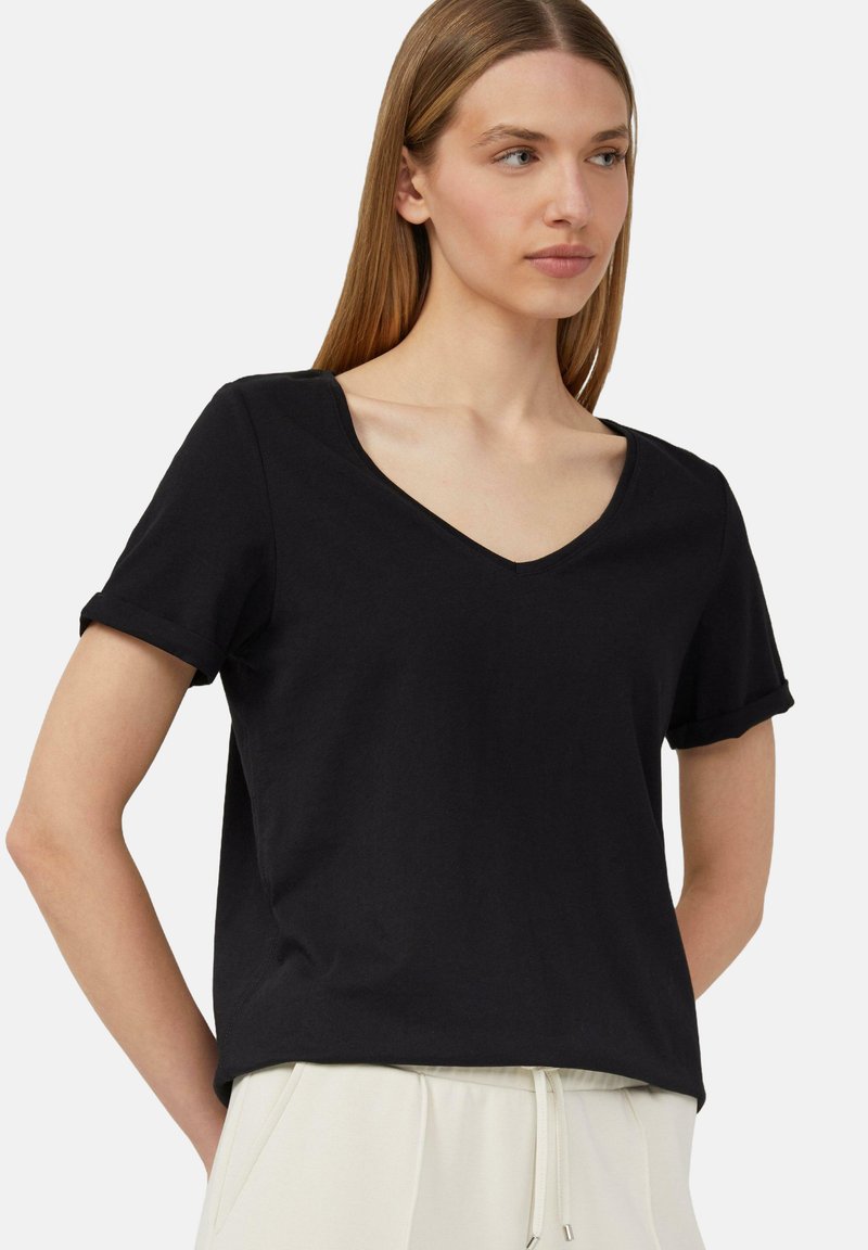 Czarna koszulka z dekoltem w serek, wykonana z miękkiej bawełny. Krótkie podwinięte rękawy i luźny krój. Gładka tekstura, minimalistyczny design i brak widocznych grafik.