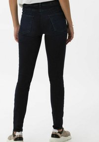 Smala jeans i mörk tvättad denim. Funktioner inkluderar bakfickor, hög midja och kontrasterande sömdetaljer. Stylad med sneakers.