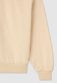 Manica di felpa beige con polsino a coste e orlo elastico su uno sfondo grigio chiaro.