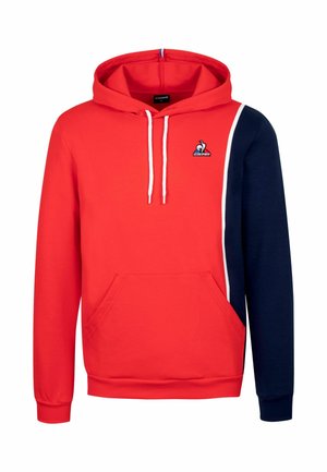 Rood en marineblauwe pullover hoodie met een voorzak, koorden en een logo op de borst. De stof lijkt zacht met een gladde textuur.