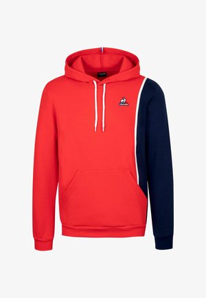 Rood en marineblauwe pullover hoodie met een voorzak, koorden en een logo op de borst. De stof lijkt zacht met een gladde textuur.