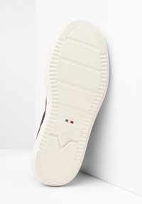 Sole di sneaker in gomma bianca con scanalature testurizzate e logo in rilievo. Presenta un dettaglio della bandiera verde e rossa e la misura della scarpa '37' impressa.