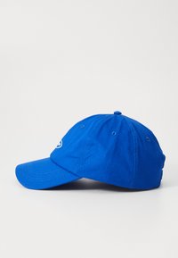 Blå bomull baseballcap med krum skjerm, seks-panel design og brodert logo foran. Har ventilasjonsluftehull.