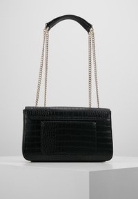 Černá kabelka z umělé kůže s texturovaným krokodýlím vzorem, plochou přední kapsou a stříbrným řetízkovým popruhem na nošení.