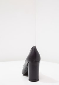 Scarpa nera con tacco alto in pelle liscia, con punta appuntita e tacco spesso, dal design elegante e minimalista.