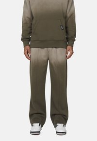 Olijfgroene hoodie met een voorkuig, gecombineerd met bijpassende ombre sweats. Het materiaal is zacht, met een gladde textuur en zichtbare stiksels.