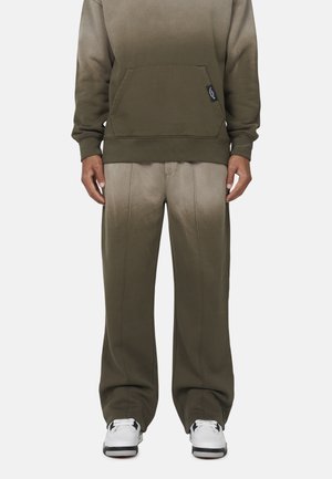 Felpa verde oliva con tasca frontale, abbinata a pantaloni sportivi ombre coordinati. Il materiale è morbido, con una texture liscia e dettagli di cucitura visibili.