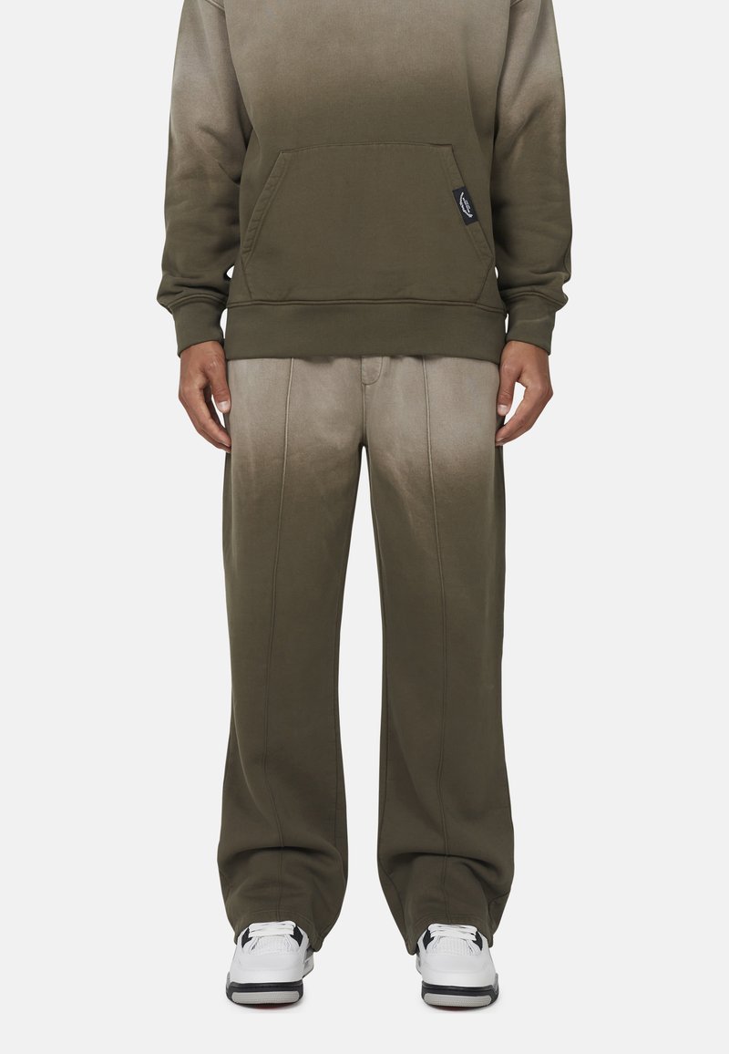 Olijfgroene hoodie met een voorkuig, gecombineerd met bijpassende ombre sweats. Het materiaal is zacht, met een gladde textuur en zichtbare stiksels.