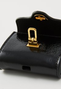 Schwarze Schultertasche aus Leder mit glänzender Oberfläche, ausgestattet mit einem goldenen Verschluss und strukturierter Textur. Enthält ein Innenfach.
