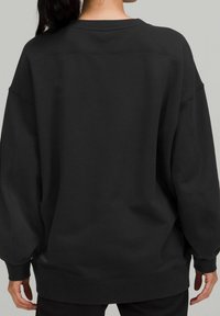 Sweatshirt oversize nero con scollo rotondo, spalle cadenti e polsini a coste, realizzato in un morbido tessuto testurizzato.