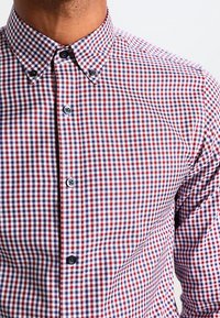 Červená a modrá kostkovaná košile s knoflíky; látka obsahuje malé čtverce, s kontrastními knoflíky a klasickým límcem.