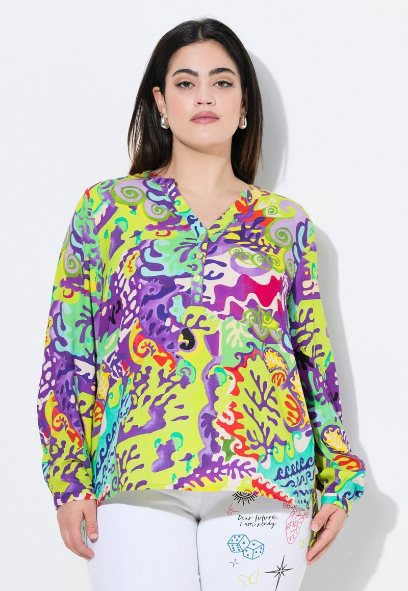 Kleurvolle lange mouw blouse in groen met abstracte paarse en rode patronen, V-hals en knoopaccenten. Zachte stof met een levendig ontwerp.