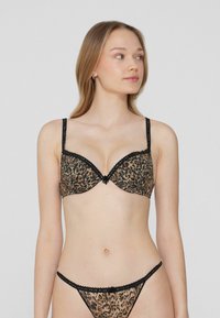 Podprsenka s leopardím vzorem a černým krajkovým lemováním, s kosticemi, nastavitelnými ramínky a odpovídajícím tanga kalhotkami s krajkovými detaily.