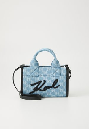 Sinine teksakangast kott, millel on houndstooth muster, must nahk aktsentides, kahekordne käepide ja õlalihm. Katses on silmapaistev skripti logo.