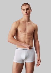 Fehér pamut boxer alsónadrág fekete Calvin Klein derékkal, testhez simuló dizájn, sima textúrával, és közép-comb hosszal.