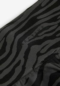 Svart och grårandig tyg med en texturerad yta och subtila varumärkesdetaljer. Designen har ett vågigt, djurmönster.